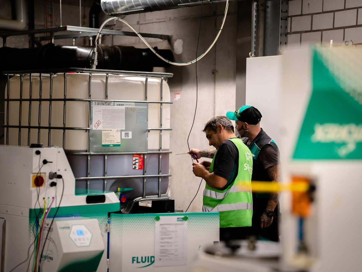 Two service technicians installing a fluid management unit next to an IBC tank