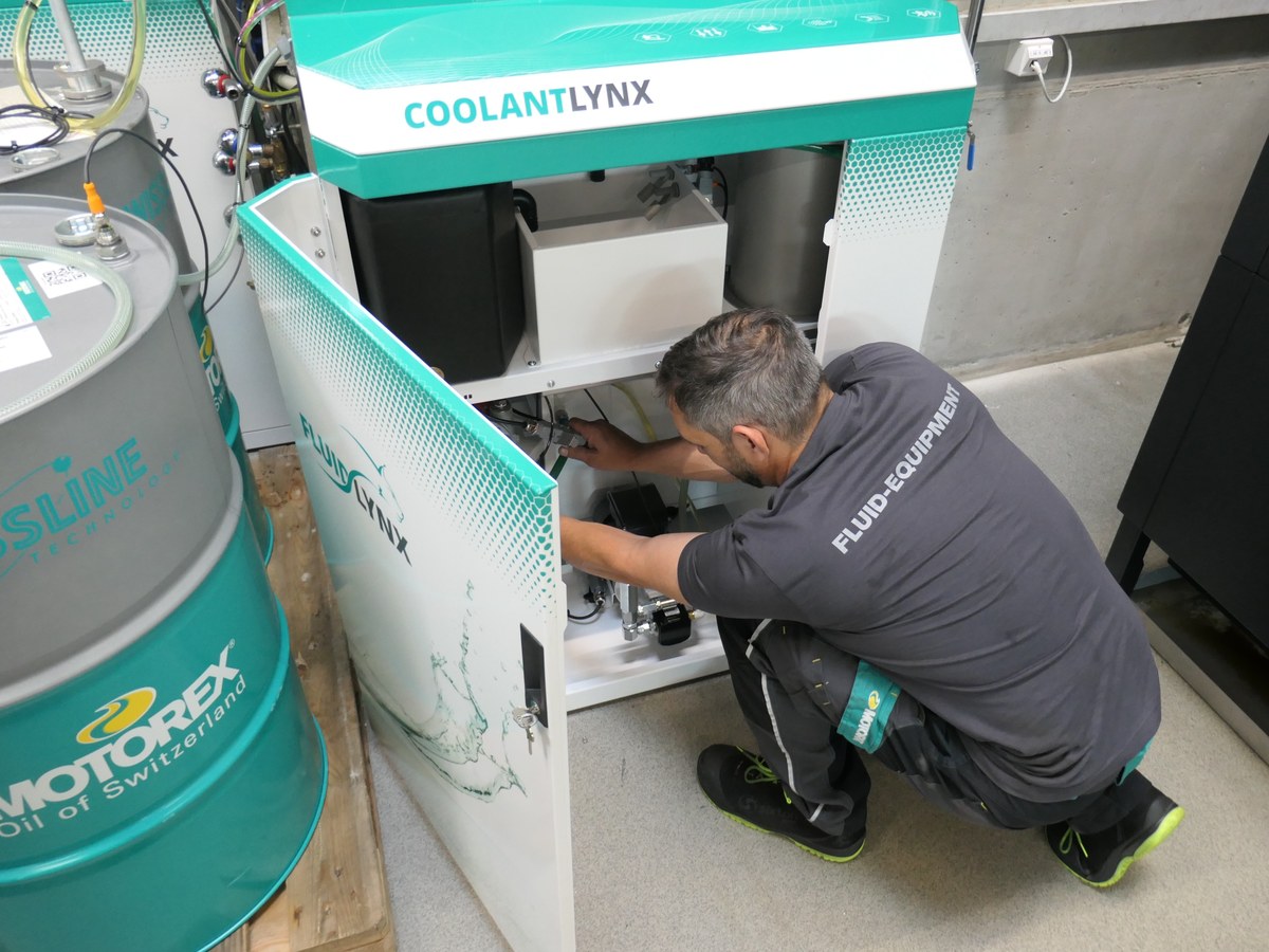 Technician installing a CoolantLynx unit next to a MOTOREX drum